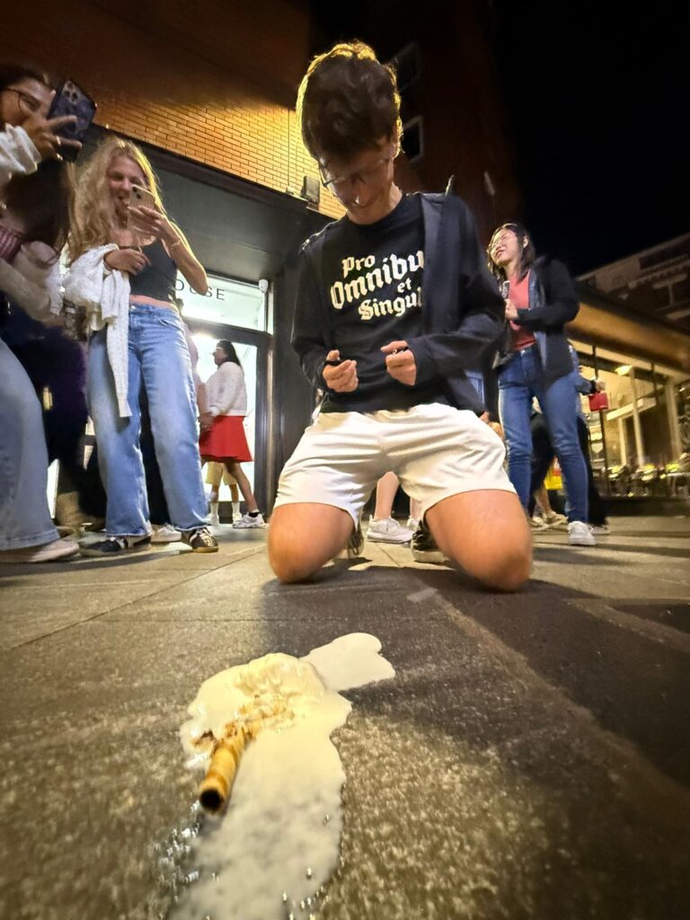 A student kneeling over his spilled ice cream.
