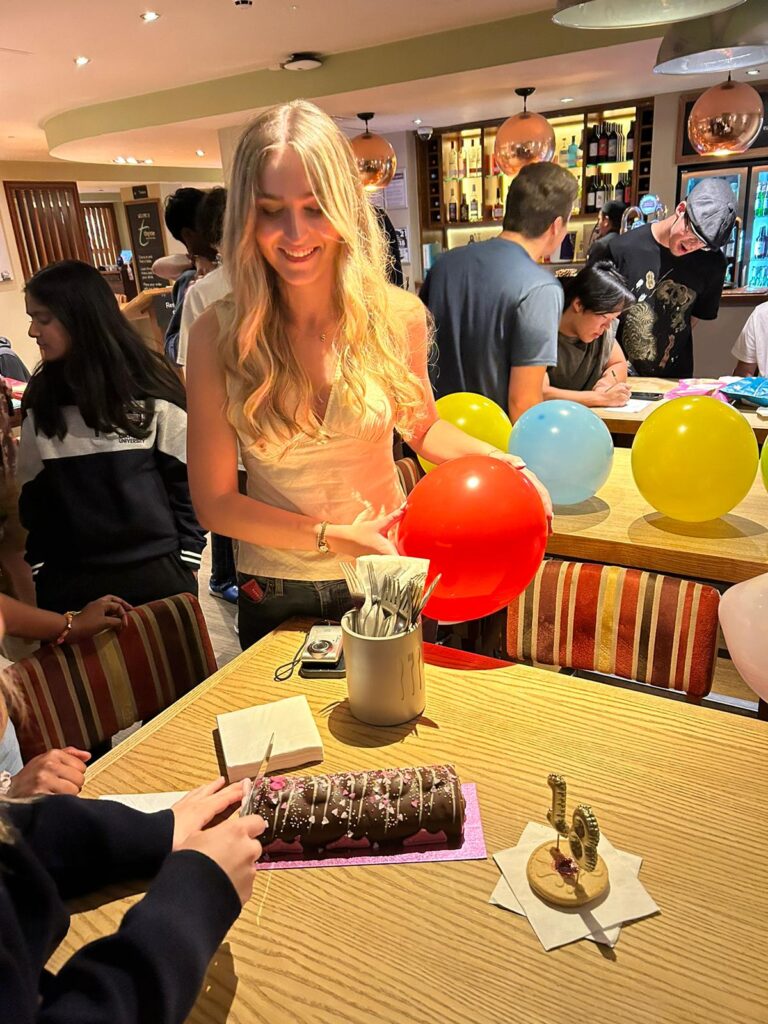 A student looking while someone cuts a cake.